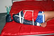 Alina bound in blue shorts and a shiny jacket