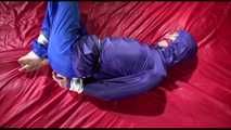 Sonja tied and gagged with ropes and a ballgag on a bed covered with a red shiny nylon cloth wearing a blue shiny nylon rain pants and a purple rain jacket (Video)