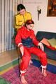 Jill tied by her friend in shiny yellow and red rainsuits