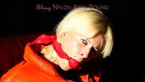 Pia tied and gagged on a chair wearing a shiny orange down jacket and a shiny blue rain pants (Pics)