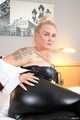 Busty blonde Frida posing in white shirt, leather corsage and black glossy leggins on bed