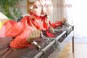 Mara tied and gagged with chains and cuffs on a bed wearing a superhot yellow shiny nylon shorts and an orange rain jacket (Pics)