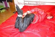 Lucy tied, gagged and hooded on a bed wearing a sexy black shiny nylon pants and a red down jacket (Pics)