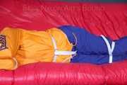 Lucy tied and gagged on a sofa wearing an orange shiny nylon rain jacket and a blue rain pants (Pics)