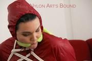 Jill tied, gagged and hooded on a red sofa wearing a black rainpants and a red rain jacket (Pics)