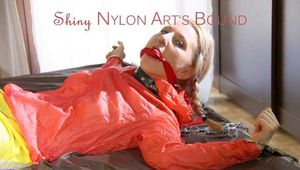 Mara tied and gagged with chains and cuffs on a bed wearing a superhot yellow shiny nylon shorts and an orange rain jacket (Pics)