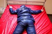 Pia hooded, tied and gagged on bed in a dark blue old school down ski suit