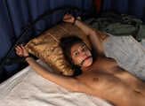 Topless barefoot Cheryl is being gagged and cuffed to the bed on-screen