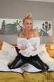 Busty blonde Frida posing in white shirt, leather corsage and black glossy leggins on bed