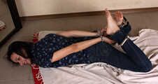 Emily in violet short-sleeve and jeans, hog-cuffed with steel cuffs, wiggles on the floor