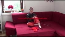 Mara ties and gagges herself with hand cuffs on a sofa wearing a supersexy orange rain pants and a black shiny nylon rain jacket (Video)
