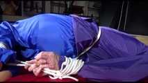 Sonja tied and gagged with ropes and a ballgag on a bed covered with a red shiny nylon cloth wearing a blue shiny nylon rain pants and a purple rain jacket (Video)