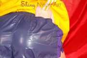 Sonja wearing a sexy blue/purple own designed shiny nylon shorts and a yellow rain jacket posing on the red sofa (Pics)