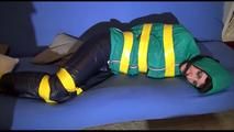 Mara tied, gagged and hooded with tape on a blue sofa wearing an blue/green rain combination (Video)