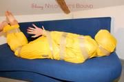 Archive girl tied and gagged by using tape on a sofa wearing an yellow rainsuit (Pics)