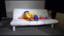 Mara with blue hairs wearing a sexy blue/yellow shiny nylon shorts and a yellow rain jacket tied and gagged with ropes and a ball gag on the sofa (Video)