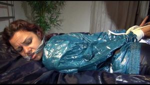 Lulu tied and gagged on a bed wearing a supersexy blue/green rainwear combination (Video)