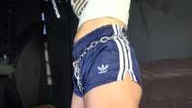 Watching sexy Sandra wearing an darkblue shiny nylon shorts and a white adidas top being tied and gagged overhead with ropes, chaines and a ballgag (Video)