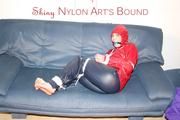 Jill tied, gagged and hooded infront of a sofa wearing a darkblue rain pants and a red rain jacket (Pics)