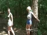 An archive girl tied and gagged on a tree by Jill both wearing shiny nylon shorts (Video)