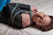 Tied arms and suspended legs in blue leggings