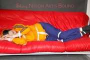 Lucy tied and gagged on a sofa wearing an orange shiny nylon rain jacket and a blue rain pants (Pics)