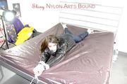 Shelly tied and gagged on a bed with downjacket and shiny rainsuit