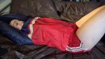 Jill tied and gagged on bed with chains and cuffs wearing shiny nylon shorts and a rain jacket (Video)