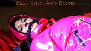 Mara tied, gagged and hooded on bed wearing a black rain pants and a pink down jacket (Pics)