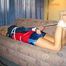 Beautiful archive girl bare feet tied and gagged in a dark blue short with light blue stripes and a red/blue rain jacket on a sofa