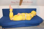 Archive girl tied and gagged by using tape on a sofa wearing an yellow rainsuit (Pics)