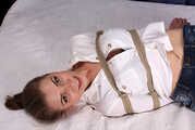 Barefoot Lisa in white shirt and jeans shorts, hogtied with hemp rope, wiggles and rolls on the bed