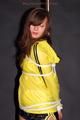 Alina tied and gagged to a pole in nylon shorts and yellow cagoule