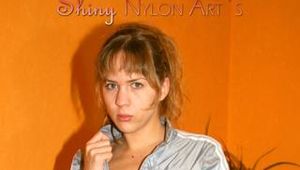 Leonie posing on a sofa wearing a grey adidas shiny nylon rainwear (Pics)