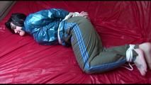 Jill tied and gagged on bed wearing a sexy grey shiny rain pants and a dark blue rain jacket (Video)