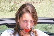 Stella tied and gagged in a grey shiny nylon catsuit in a car