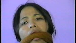24 Yr OLD VIETNAMESE DAISY IS CLEAVE GAGGED, BAREFOOT, MOUTH STUFFED WITH NYLON ANKLE STOCKING, STUFFS HER OWN MOUTH, TIED ON BED & HANDGAGGED WITH BLACK LEATHER GLOVE (D55-5)