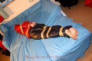 one of our archive girls tied and gagged in shiny nylon rainwear
