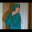Mara wearing a blue rain pants and a green rain jacket preparing and appraising herself before going out (Video)