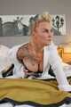 Busty blonde Frida posing in white shirt, leather corsage and black glossy leggins on bed