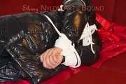 Lucy wearing a black shiny nylon rainh pants and a black down jacket tied and gagged on a sofa (Pics)