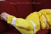 Mara tied, gagged and hooded with tape on a red sofa wearing shiny yellow rainwear (Pics)