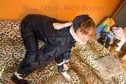 Leoni tied and gagged on a sofa wearing a sexy shiny nylon pants and a rain jacket (Pics)