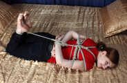 Ballgagged barefoot Tammy in red t-shirt and black jeans, hogtied with hemp rope