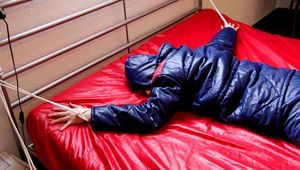 Pia hooded, tied and gagged on bed in a dark blue old school down ski suit