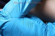 Pia tied and gagged on a bed wearing a shiny red nylon shorts and a blue rain jacket (Pics)