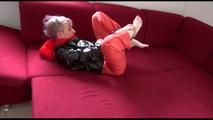 Mara ties and gagges herself with hand cuffs on a sofa wearing a supersexy orange rain pants and a black shiny nylon rain jacket (Video)