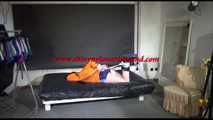 Lucy tied and gagged on a bed wearing a blue shiny nylon shorts and an orange shiny nylon rain jacket (Video)