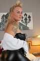 Busty blonde Frida posing in white shirt, leather corsage and black glossy leggins on bed