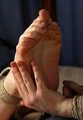 Barefoot Doris in bra and shorts, hogtied with hemp rope, rolls and wiggles on the bed